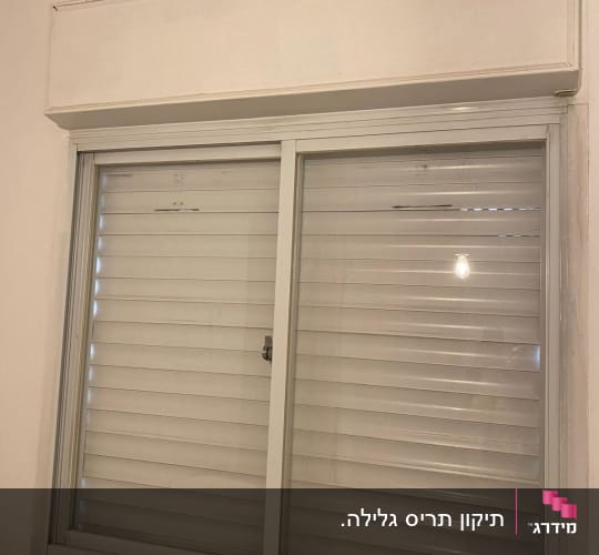 חלון עם תריסים סגורים על קיר לבן